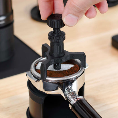 Hand twisting the ARO Headspace Setter to trim off excess grounds in the espresso basket.