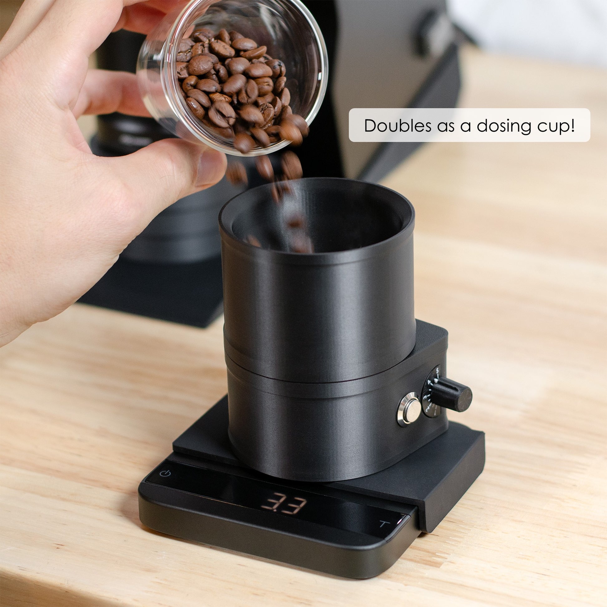 Close-up of a person pouring coffee beans into the ARO Slow Feeder on a digital scale, with text overlay “Doubles as a dosing cup!”