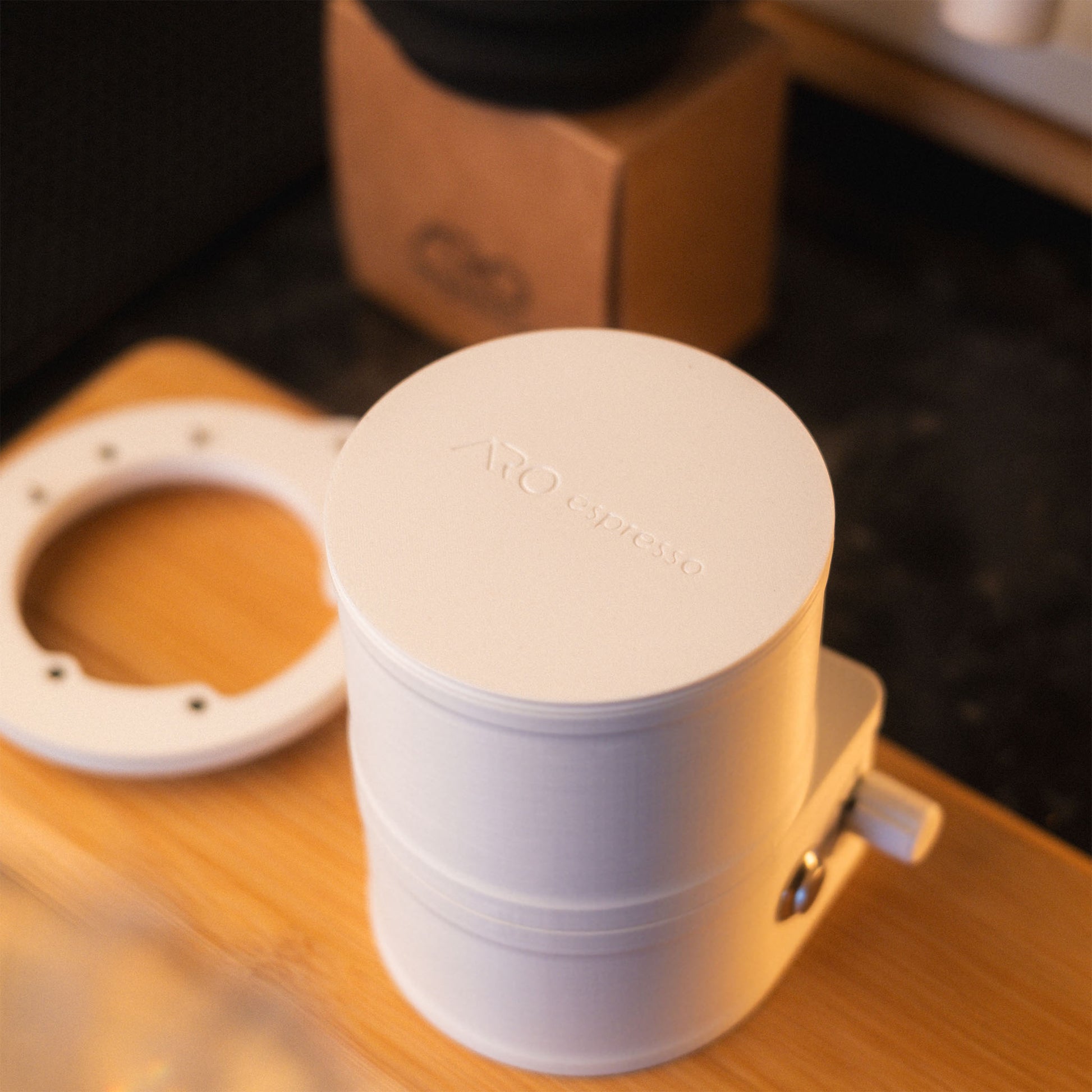 Fully assembled white ARO Espresso slow feeder sitting on a wooden board with the ARO logo visible on the lid.